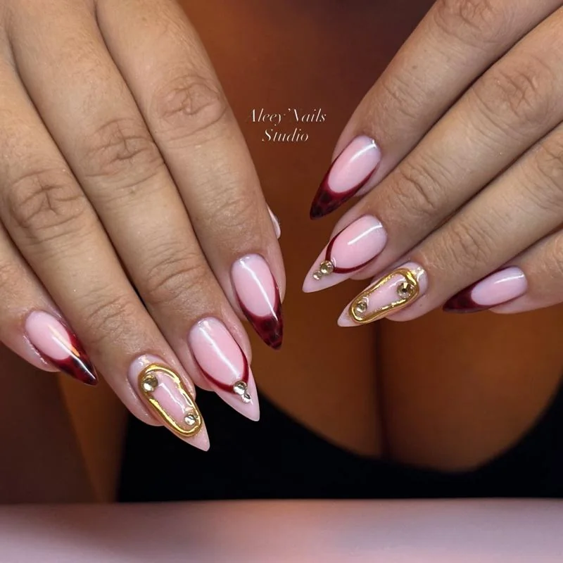 Ongles amande French bordeaux avec décorations dorées